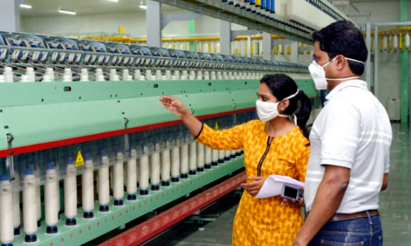 Woman and man inspecting machine in a factor